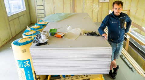 Bastian Faaness står ved paller med isolasjon og snakker om bærekraftig utvikling i byggebransjen