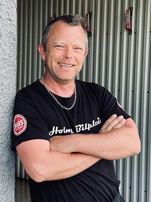 Daglige leder Arnt smiler stort ved verkstedet